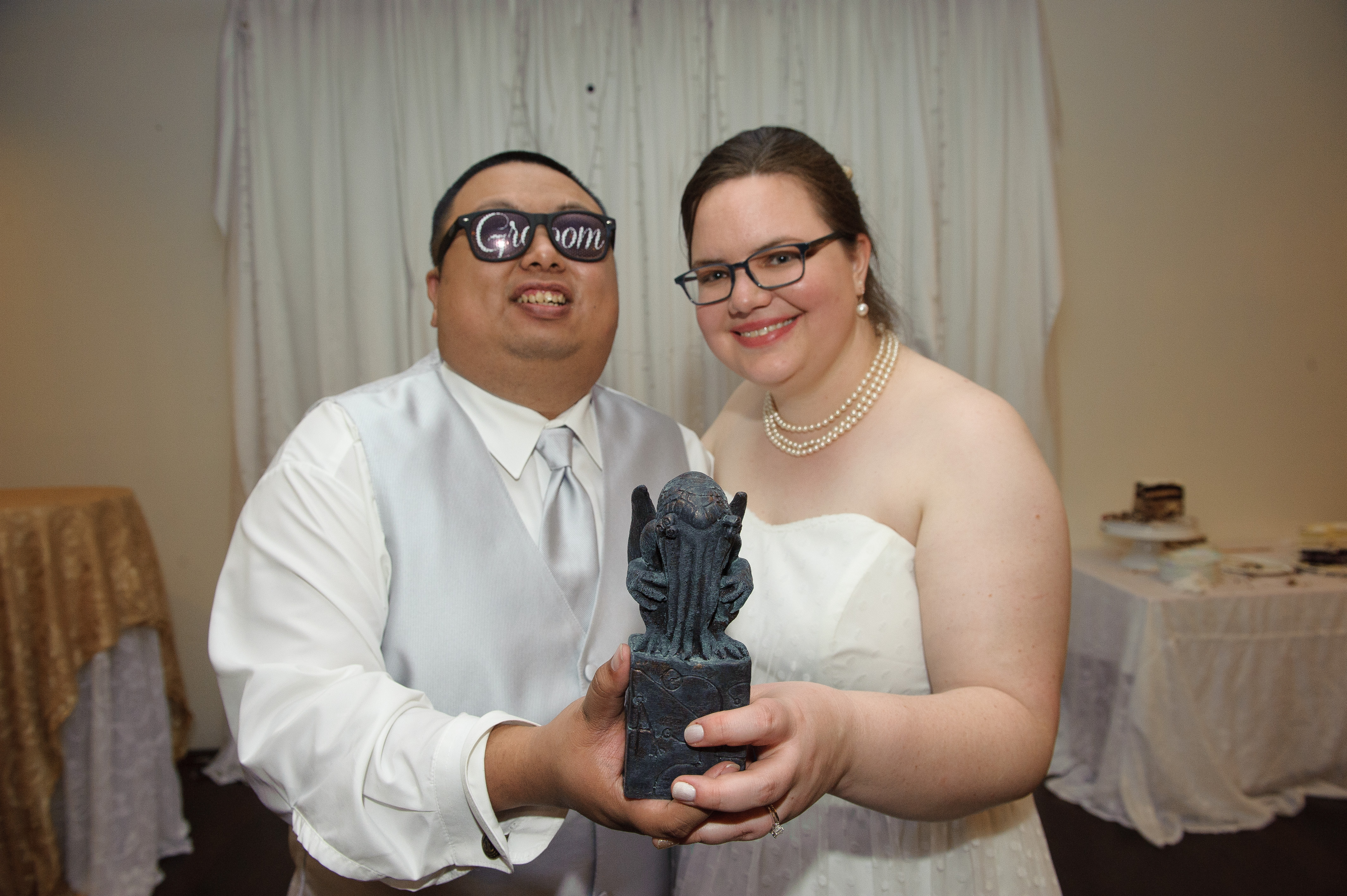 Megan and Aser hold out a Cthulhu statue after their wedding.